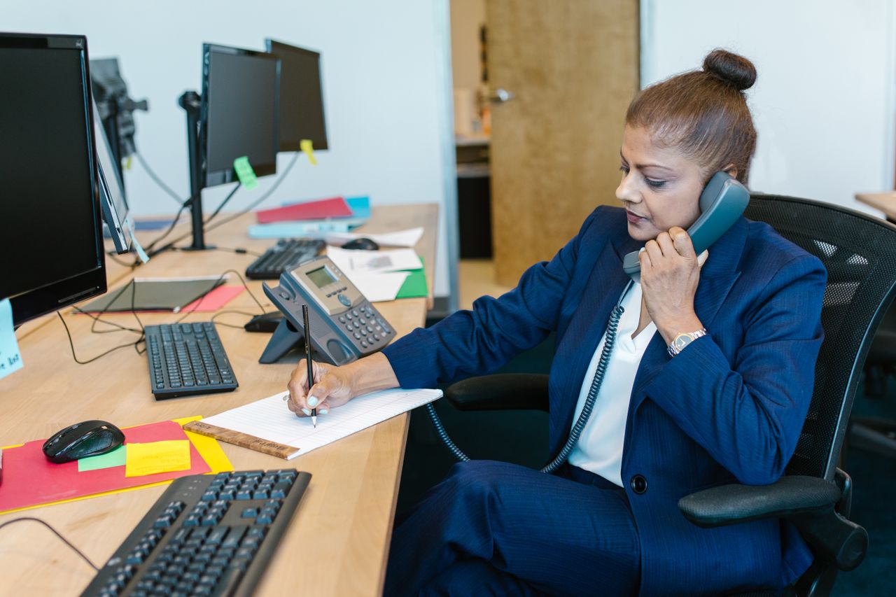 A person writing call notes at a desk